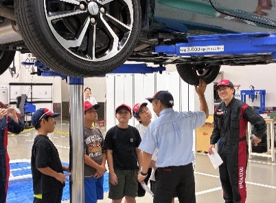 リフトで持ち上げた車の下を見学する様子